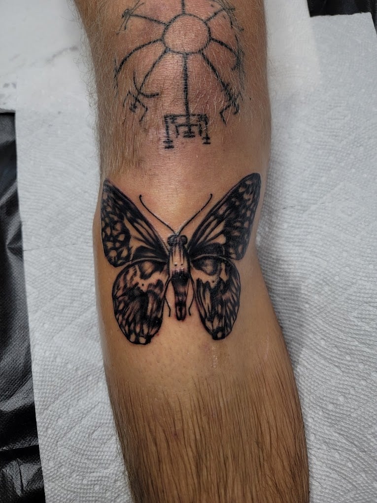 Black and grey skull and butterfly tattoo on forearm, done at Soul Stone Tattoo